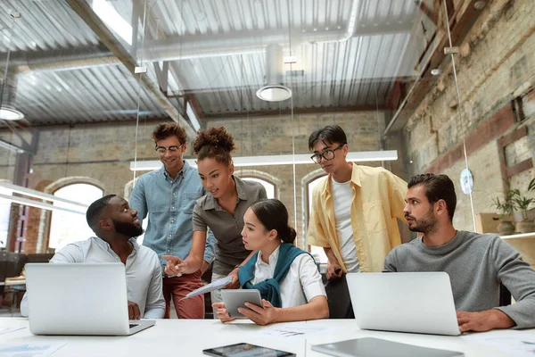 Erfolgreiche Zusammenarbeit. Junge Geschäftsleute in Freizeitkleidung nutzen moderne Technologien und arbeiten im Kreativbüro gemeinsam an einem neuen Projekt — Stockfoto