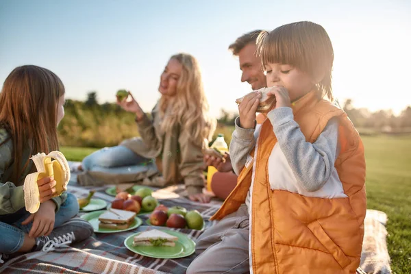 Det smakar gott. Lycklig familj tillbringa tid i parken på en solig dag — Stockfoto