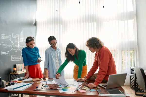 Perfect teamwork. Professional team of young web designers working on a new project together and discussing ideas while standing in the modern and bright office — Stock Photo, Image