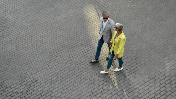 Vista dall'alto della coppia caucasica di mezza età in elegante usura che si tiene per mano mentre cammina insieme per la strada della città — Foto Stock