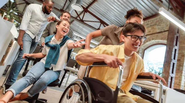 ポジティブに。若い幸せなアジア人男性車椅子で楽しい彼の同僚と現代オフィスで — ストック写真