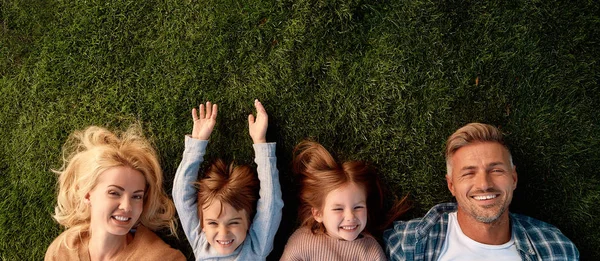 Mantén la calma y ama a tu familia. Familia feliz de cuatro tumbados sobre hierba verde Fotos de stock libres de derechos