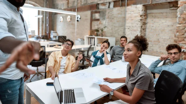 No somos solo un equipo. Grupo de equipo multicultural escuchando atentamente a su líder de equipo mientras tiene una reunión de negocios en la oficina moderna —  Fotos de Stock