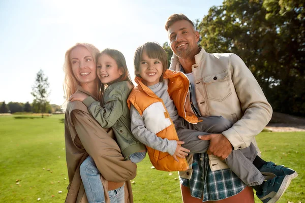 Un week-end parfait. Les jeunes parents et leurs enfants profitent de la journée ensoleillée ensemble tout en se tenant sur une prairie verte — Photo