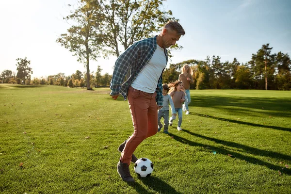 On adore le football. Famille heureuse jouant avec une balle sur prairie — Photo