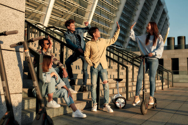 Мы команда. Группа друзей со скутерами и сегвеями в солнечный день
