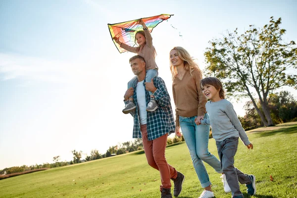 Dzieci uczą się uśmiechać od rodziców. Szczęśliwa rodzina grająca latawca. Weekend na świeżym powietrzu — Zdjęcie stockowe