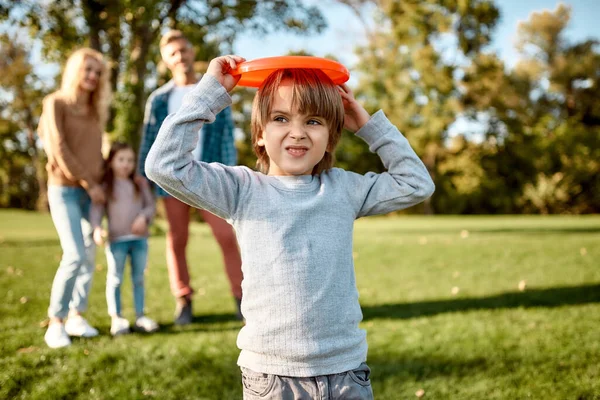 Opatrnost a důvěra. Malý chlapec hraje frisbee v parku za slunečného dne — Stock fotografie