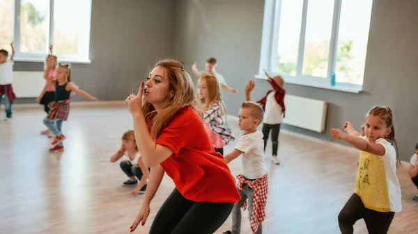 State zitti. Ritratto di una giovane insegnante di danza femminile che tiene l'indice sulle labbra mentre balla con i bambini nello studio di danza. Lezione di coreografia — Foto Stock