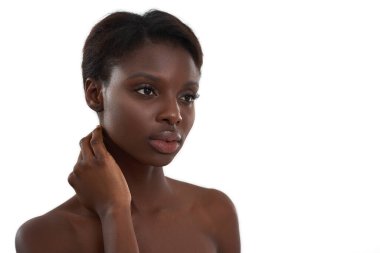 Sağlıklı ve güzel bir cilt. Çıplak omuzlarıyla boynuna dokunan ve beyaz arka planda duran genç ve şehvetli bir Afrikalı kadının portresi.