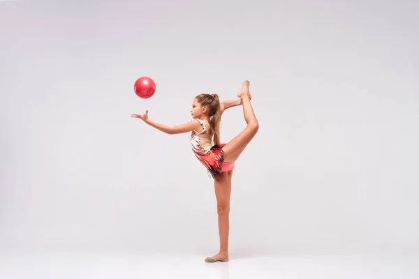 Flipping Fun. Full-length shot of flexible cute girl child gymnast doing acrobatic exercise using ball isolated on a white background. Sport, training, rhythmic gymnastics, active lifestyle concept — Stock Photo, Image