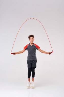 Ben böyle zıplıyorum. Zıplama halatı kullanarak atlayan, fitness yapan bir gencin tam boy fotoğrafı. Beyaz arka planda izole edilmiş. Spor, eğitim, fitness, aktif yaşam tarzı konsepti