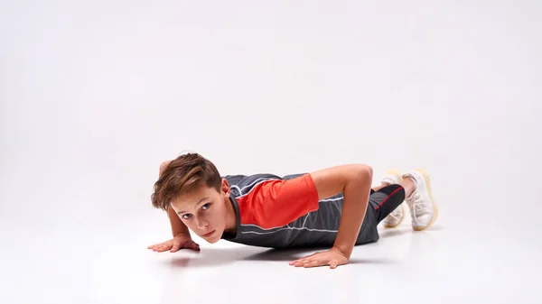 Limitando los límites. Fotografía completa de un adolescente que practica deporte, mirando a la cámara mientras hace flexiones. Aislado sobre fondo blanco. Formación, concepto de estilo de vida activo — Foto de Stock