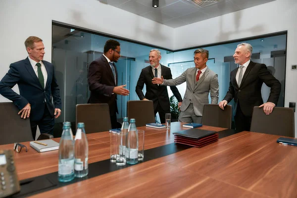 Χαίρομαι που σας γνωρίζω. Αφρικανοί και Ασιάτες επιχειρηματίες με επίσημη ενδυμασία σφίγγουν το χέρι μετά από επιτυχή συνάντηση ενώ στέκονται με τους συναδέλφους τους στο σύγχρονο γραφείο — Φωτογραφία Αρχείου