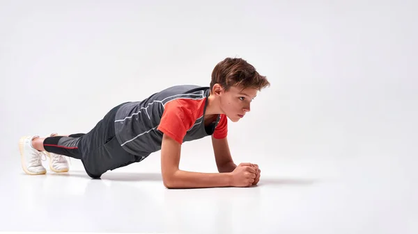 Mejórate. Foto completa de un adolescente practicando deporte, luciendo enfocado mientras hace flexiones. Aislado sobre fondo blanco. Formación, concepto de estilo de vida activo —  Fotos de Stock