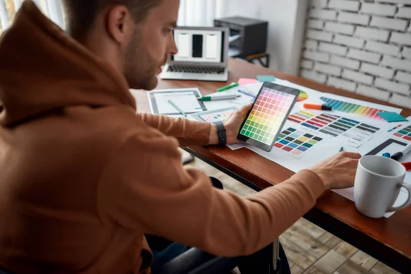 Gehakte foto van gefocuste jonge mannelijke Ux Ui-ontwerper in een rolstoel die kleurstalen kiest voor nieuwe mobiele app terwijl hij op zijn creatieve werkplek werkt — Stockfoto