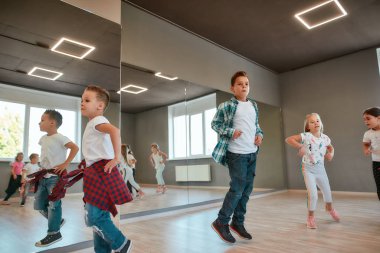Full of energy. Little happy boys and girls running and jumping in the dance studio. Warming up before dance class