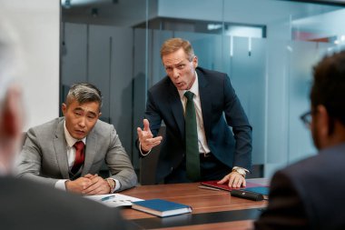 Feeling angry. Furious mature businessman in formal wear shouting at his colleagues while having a meeting in the conference room