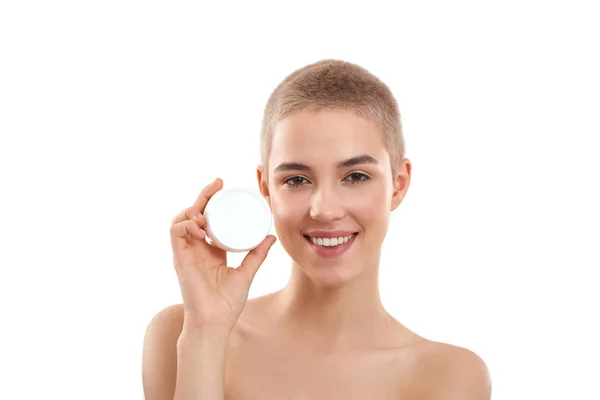 Perfect face cream. Young attractive blonde woman with short haircut demonstrating cosmetic product and smiling at camera while standing in studio against white background — Stok fotoğraf
