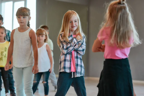Estilo hip hop. Grupo de lindos niños positivos aprendiendo una danza moderna en el estudio de baile. Clase de coreografía —  Fotos de Stock
