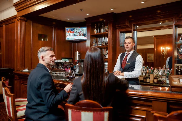 Aproveite a noite. Duas pessoas de negócios casuais em um bar do hotel à noite conversando enquanto toma dois copos de vinho tinto após o check-in — Fotografia de Stock
