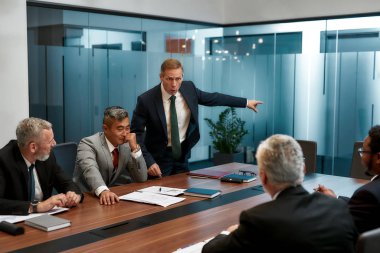 Get out of here right now. Angry mature businessman in formal wear asking employee to leave business meeting. Furious boss shouting at his colleagues while having a meeting in the conference room