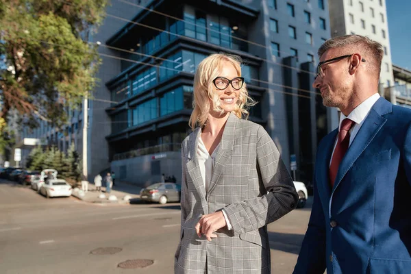 Lets take a little walk. Cheerful man and woman in classic wear discussing something and smiling while walking outdoors — Stockfoto