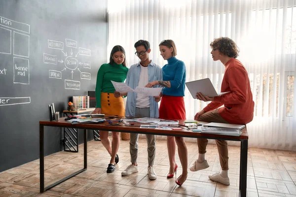 Creating new website. Creative group of four young designers discussing new project while having a meeting in the modern office. Web design concept — Stockfoto