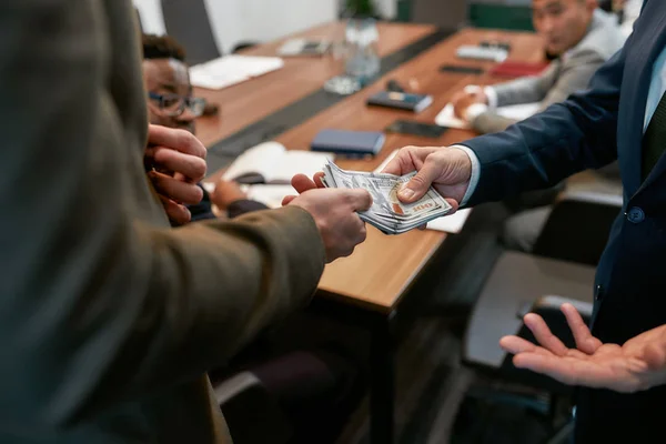 Foto recortada de un hombre de negocios dando dinero a su pareja mientras tiene una reunión en la oficina moderna — Foto de Stock