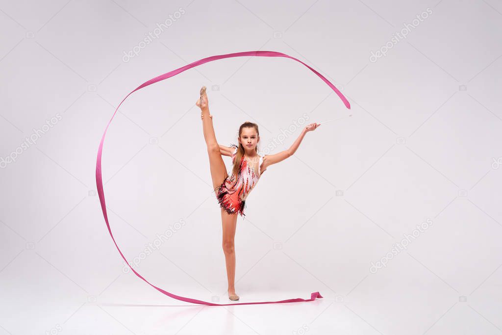 Defeat Gravity. Full-length shot of flexible girl child gymnast doing acrobatic exercise using ribbon isolated on a white background. Sport, training, rhythmic gymnastics, active lifestyle concept
