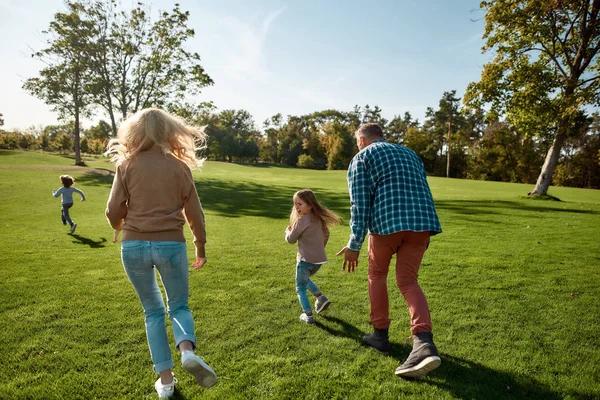 La vie est courte, passez-la en famille. Famille excitée courir à l'extérieur par une journée ensoleillée — Photo