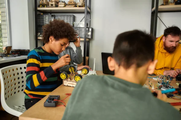 Aprender nunca agota la mente. Niño usando destornillador mientras fija pernos en un vehículo robot. Niños inteligentes y educación STEM . — Foto de Stock