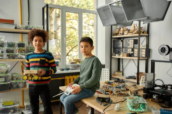 Alto rendimiento entregado. Dos chicos mirando a la cámara con una sonrisa después de terminar de hacer un vehículo robot en una clase de tecnología. Niños inteligentes y educación STEM . — Foto de Stock