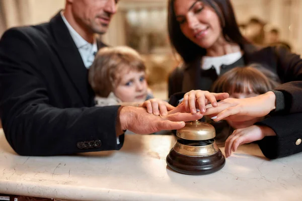 누르 세요. 호텔 리셉션 데스크에 있는 행복 한 가족 확인. 호텔 리셉션에 서서 부모님 과 함께 서비스 벨을 울리는 아들 과 딸. — 스톡 사진