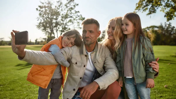 Mira la cámara. Familia feliz tomando selfies al aire libre —  Fotos de Stock