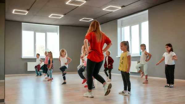 Balla per i bambini. Gruppo di bambini e bambine che ballano mentre fanno lezione di coreografia nello studio di danza. Insegnante di danza e bambini — Foto Stock