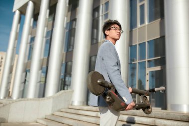 Hareket kabiliyetine karşılık anahtarın. Katlanmış e-scooterlı genç bir ofis çalışanı.