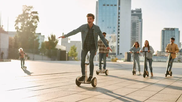 車を持って、人生を得る。晴れた日にキックスクーターやセグウェイに乗る友人のグループ — ストック写真