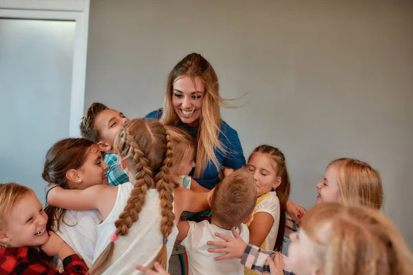 Grupo de niños felices abrazando a su maestro de baile mientras están en el estudio. Relación entre el profesor y los niños — Foto de Stock