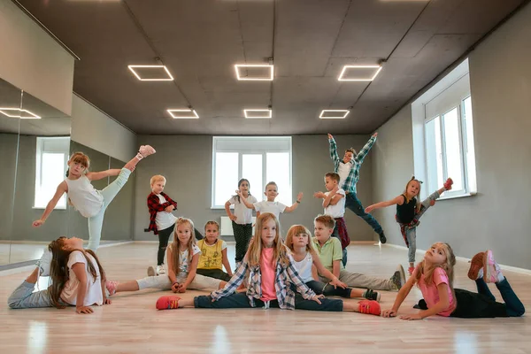 Продолжай танцевать. Группа счастливых маленьких мальчиков и девочек в модной одежде, позирующих вместе в танцевальной студии. Танцевальная команда . — стоковое фото