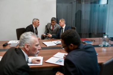Resmi olarak çok kültürlü iş adamları, modern ofisteki ortaklarla toplantı yaparken sözleşme koşullarını tartışırlar.