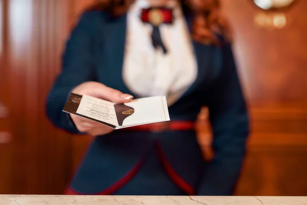 Для тебе. Обрізаний знімок молодої жінки-виконавця на рецепції готелю, що працює, даючи привілейовану особисту картку гостю — стокове фото
