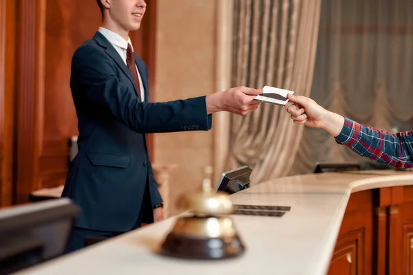 Специальные предложения. Обрезанный снимок молодого руководителя на ресепшене отеля, работающего, дающего привилегированную персональную карту гостю — стоковое фото