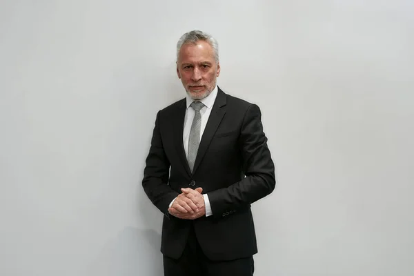 Portrait of confidence. Successful mature businessman in classic wear looking at camera while standing against grey background — Stockfoto