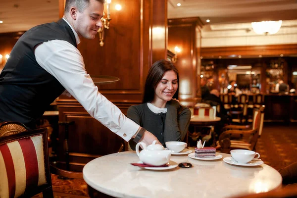Put customers first. Confident waiter serving desserts and coffee to costumers. Couple having breakfast in hotel restaurant — 스톡 사진