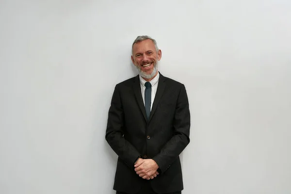 Happy business expert. Portrait of cheerful mature businessman in classic wear looking at camera and smiling while standing against grey background — Stockfoto