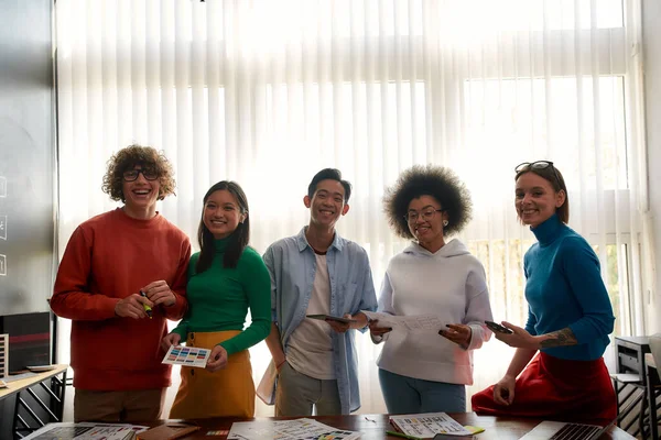 Perfect team. Group of multicultural creative people looking at camera and smiling while standing in the modern office. Young and professional designers working on a new project — Φωτογραφία Αρχείου