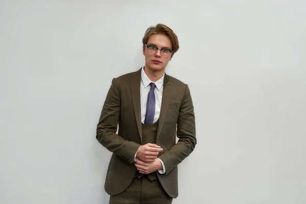 Handsome and successful. Portrait of young confident businessman in classic wear adjusting his sleeves and looking at camera while standing against grey background — Stok fotoğraf