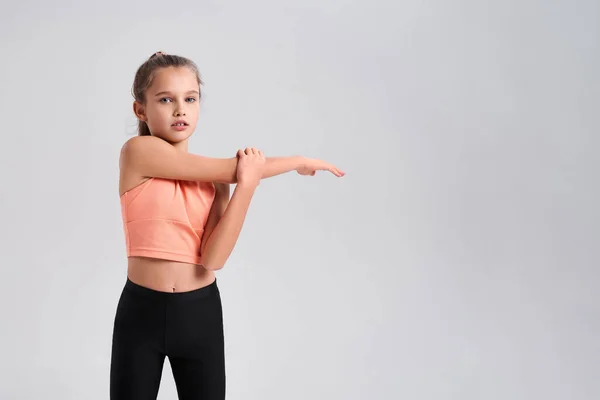 Gioco a fitness. Flessibile bambina carina guardando la fotocamera mentre fa esercizio isolato su uno sfondo bianco. Sport, allenamento, fitness, stile di vita attivo. Colpo orizzontale — Foto Stock