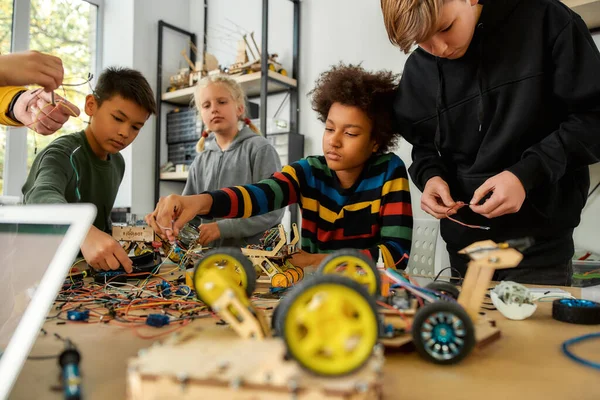 First Attempts In Learning. Diligent girl and boys making a vehicle at a technology class. Smart kids and STEM education. Selective focus — Stok fotoğraf